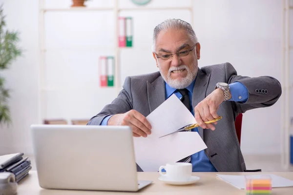 Stary męski pracownik trzymający nożyczki w biurze — Zdjęcie stockowe