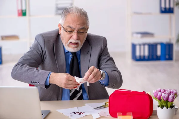 Oude mannelijke werknemer snijdt zijn hand in het kantoor — Stockfoto