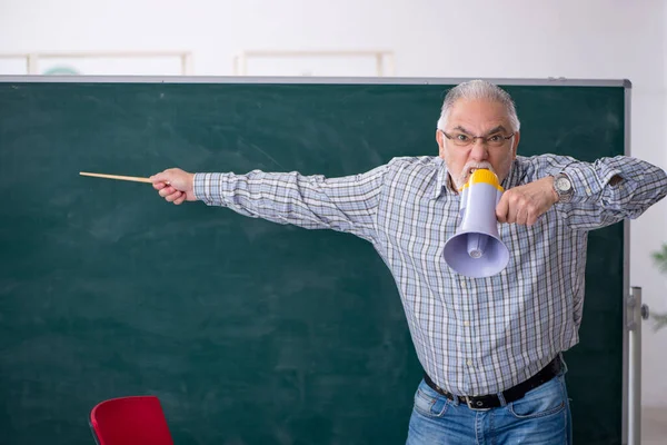 Alter männlicher Lehrer mit Megafon im Klassenzimmer — Stockfoto