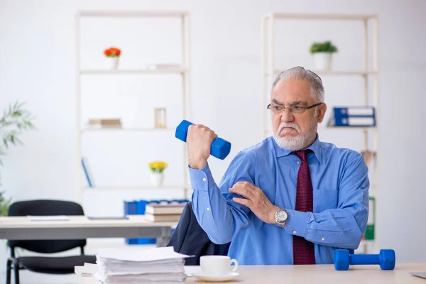 Starý muž zaměstnanec dělá sportovní cvičení během přestávky — Stock fotografie