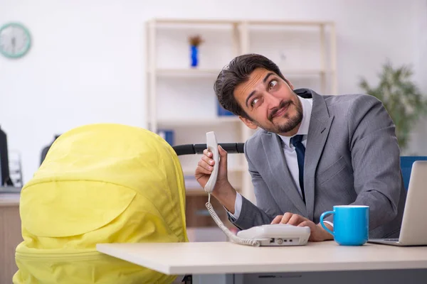 Junge männliche Mitarbeiter kümmern sich um Neugeborene am Arbeitsplatz — Stockfoto