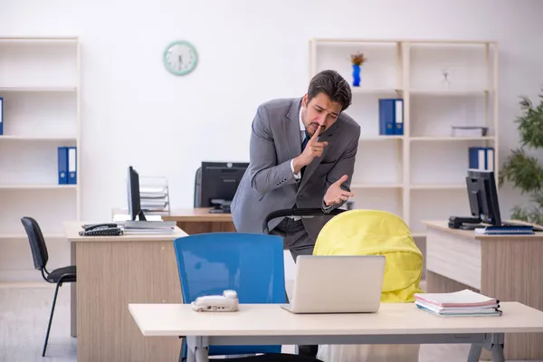 Junge männliche Mitarbeiter kümmern sich um Neugeborene am Arbeitsplatz — Stockfoto