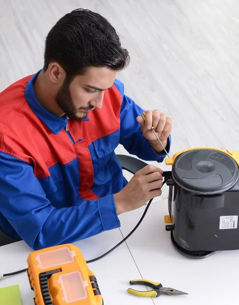 Man repairman repairing vacuum cleaner at service center