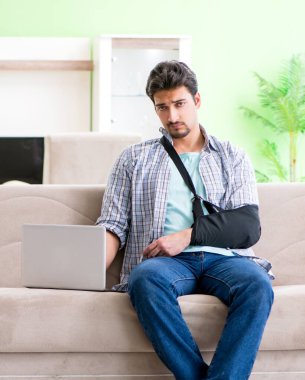 Eli yaralı genç bir öğrenci kanepede oturuyor.