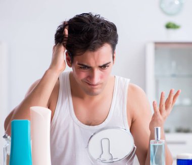 Genç yakışıklı adam aynaya bakıyor.