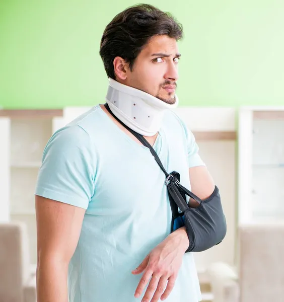 Giovane studente uomo con collo e mano lesioni a casa — Foto Stock
