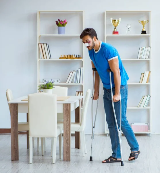 Injured man with crutches recovering at home — Stock Photo, Image