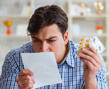 Kanepede ilaç ve reçeteyle oturan genç adam.