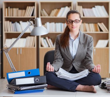 İş kadını ofiste meditasyon yapıyor.