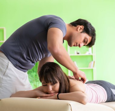 Genç doktor masör hastaya masaj yapıyor.