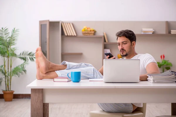 Ung manlig anställd som arbetar hemifrån under en pandemi — Stockfoto