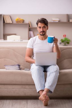 Genç erkek çalışan salgın sırasında evden çalışıyor.