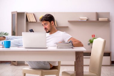 Genç erkek çalışan salgın sırasında evden çalışıyor.