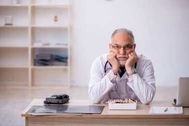 Hastanede çalışan yaşlı erkek doktor.