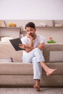 Genç erkek çalışan salgın sırasında evden çalışıyor.