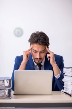 Genç bir erkek çalışan ve ofiste çok fazla iş var.