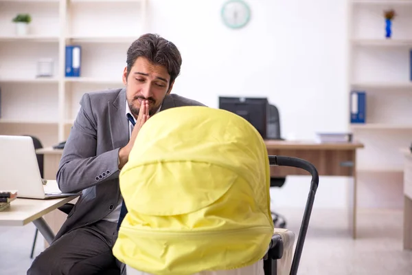 Junge männliche Mitarbeiter kümmern sich um Neugeborene am Arbeitsplatz — Stockfoto