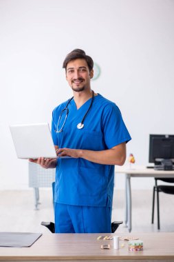 Klinikte çalışan genç erkek doktor.