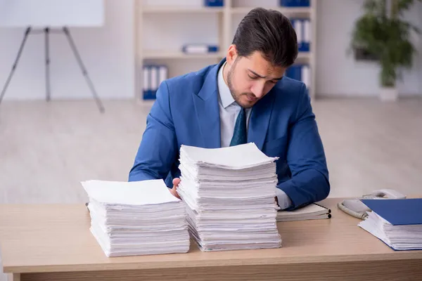 Young male employee unhappy with excessive work in the office — Stock Photo, Image