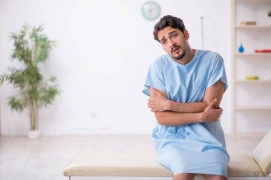 Genç erkek hasta hastanede doktor bekliyor.