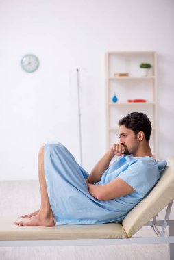 Genç erkek hasta hastanede doktor bekliyor.