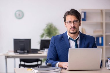 Ofisteki aşırı işten memnun olmayan genç bir erkek işçi.