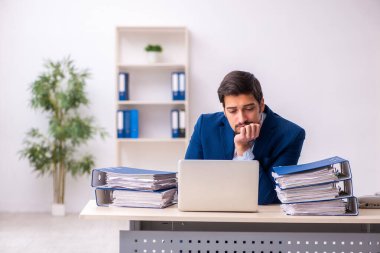 Ofisteki aşırı işten memnun olmayan genç bir erkek işçi.