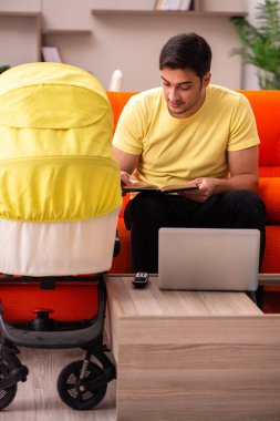 Genç adam evde yeni doğan çocuğa bakıyor.