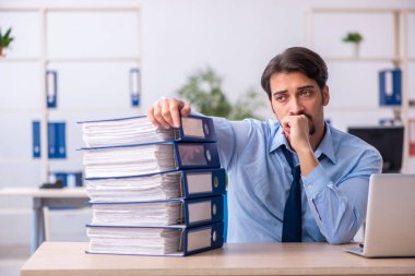 Genç bir erkek çalışan ve ofiste çok fazla iş var.