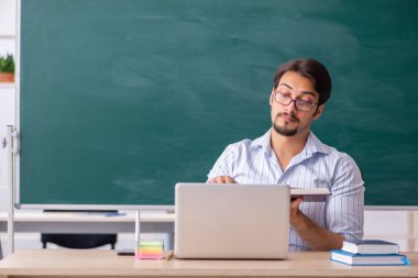 Tahtanın önündeki genç erkek öğretmen.