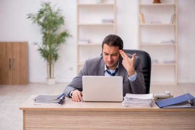 Ofisteki aşırı işten memnun olmayan genç bir erkek işçi.