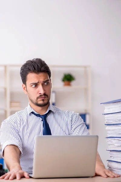 Joven empleado masculino y demasiado trabajo en la oficina — Foto de Stock