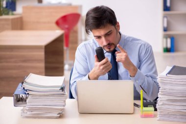 Genç bir erkek çalışan ve ofiste çok fazla iş var.