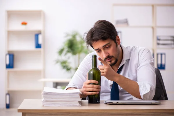 Junge alkoholabhängige Angestellte sitzt im Büro — Stockfoto