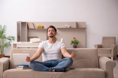 Genç erkek öğrenci salgın sırasında evde çalışıyor.