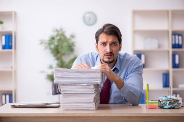 Genç bir erkek çalışan ve ofiste çok fazla iş var.