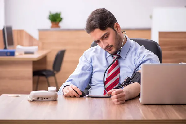 Giovane dipendente maschio affetto da ipertensione sul posto di lavoro — Foto Stock