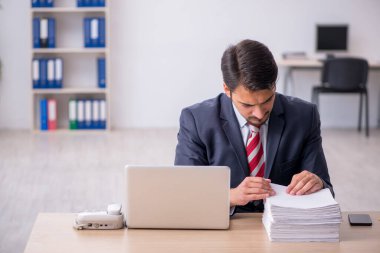 Genç erkek çalışan işyerinde oturuyor.