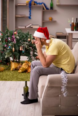 Genç adam Noel partisinden sonra daireyi temizliyor.