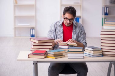 Genç bir erkek öğrenci ve sınıfta çok fazla kitap var.