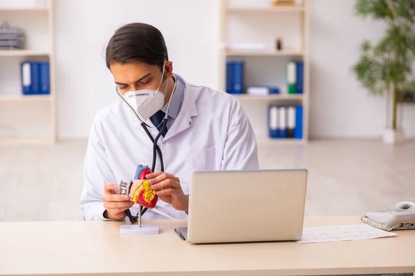 Jonge mannelijke cardioloog werkzaam in de kliniek tijdens de uitbreiding — Stockfoto