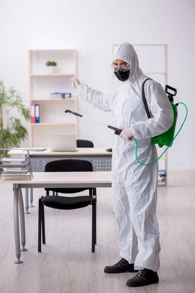 Contratista masculino joven desinfectando oficina durante pandemia —  Fotos de Stock