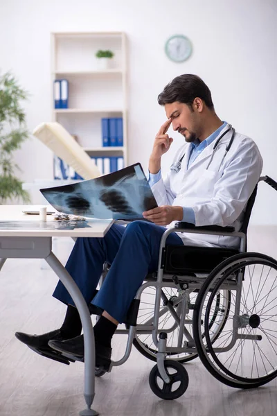 Jonge mannelijke arts in rolstoel werkzaam in de kliniek — Stockfoto