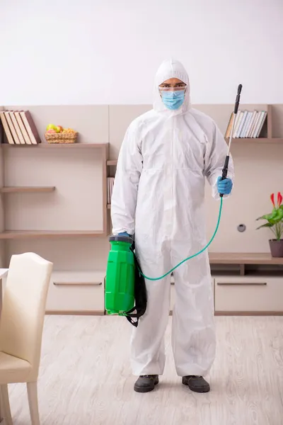 Jovem empreiteiro masculino desinfetando em casa — Fotografia de Stock