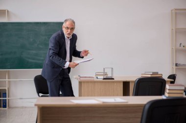 Tahtanın önünde yaşlı bir erkek öğretmen.