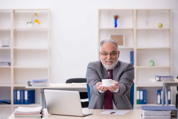 Gammal manlig anställd dricker kaffe under rasten — Stockfoto