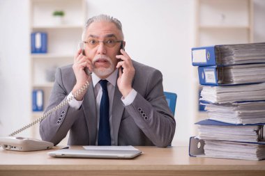 Ofisteki aşırı işten memnun olmayan yaşlı bir erkek işçi.