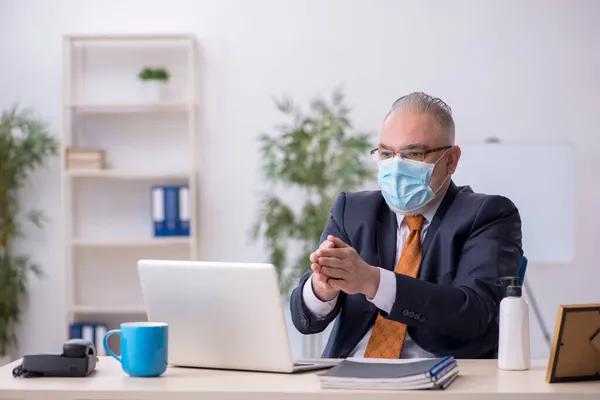 Gammal manlig anställd som arbetar på kontoret under pandemin — Stockfoto