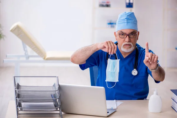Oude mannelijke arts werkzaam in de kliniek tijdens pandemie — Stockfoto