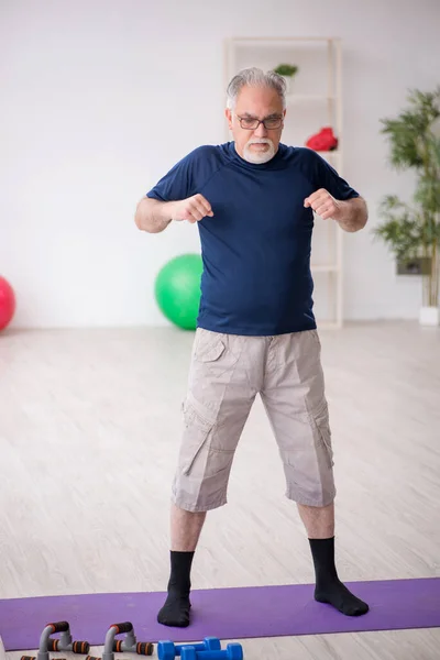 Starý muž dělá sportovní cvičení uvnitř — Stock fotografie